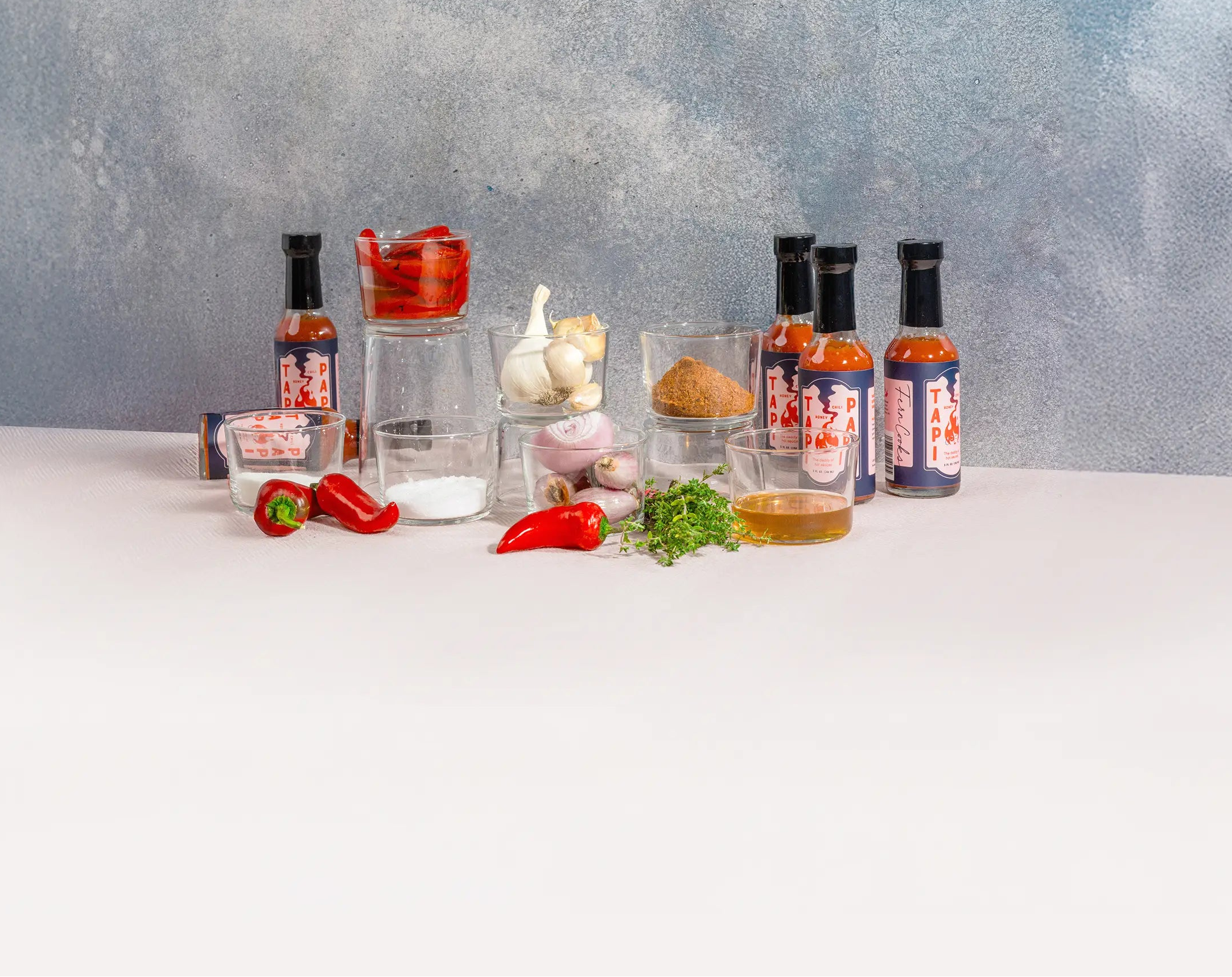 Tapi Papi hot sauce bottles with its ingredients on a light-colored surface.